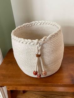 a white rope basket sitting on top of a wooden table