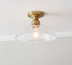 a light that is on the ceiling with a glass bowl in front of it's head