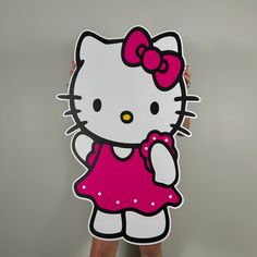 a woman holding up a hello kitty cutout