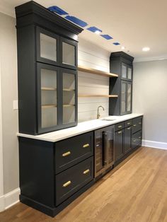 an empty kitchen with black cabinets and white counter tops, wood flooring and hard wood floors