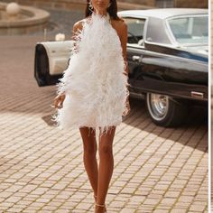 a model walks down the runway in a white feathered dress