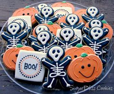 decorated cookies in the shape of skeletons and jack - o'- lanterns on a clear platter