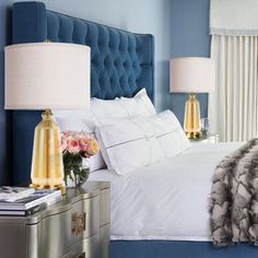 a bedroom with blue walls, white bedding and two lamps on the nightstands