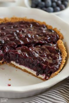 a close up of a pie on a plate with blueberries in the back ground