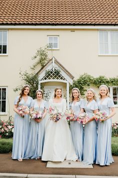 a group of women standing next to each other in front of a building with flowers