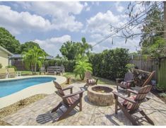 a backyard with a fire pit, chairs and a pool in the backround