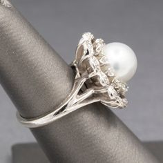 a white pearl and silver ring on top of a piece of cloth