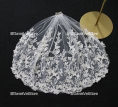 a veil with white flowers on it next to a gold circle and a black background