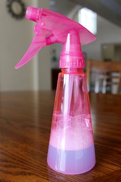 a pink spray bottle sitting on top of a wooden table