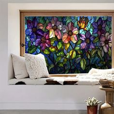 a stained glass window with flowers on it in a white living room, next to a table and chair