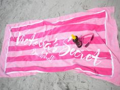 a pink and white towel with the words victoria's secret on it laying on sand