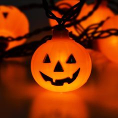 glowing jack o lantern pumpkins on a string with lights in the dark behind them