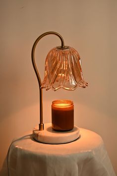 a table with a lit candle on it and a glass vase sitting next to it