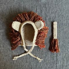 a crocheted lion hat with tassels sits on top of a gray surface