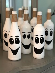 white bottles with faces painted on them sitting on a counter