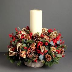 a candle sits on top of a basket filled with candy canes and holly berries