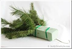 a green wrapped present sitting on top of a white table next to a pine tree