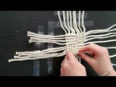 someone is working on something that looks like a cross made out of white string and beads