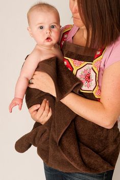 a woman holding a baby wrapped in a brown towel