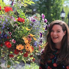 a woman standing next to a bunch of flowers