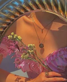 a close up of a woman holding flowers in front of a mirror with the reflection of her face