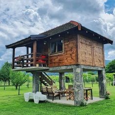 a small wooden cabin sitting on top of a lush green field under a cloudy sky