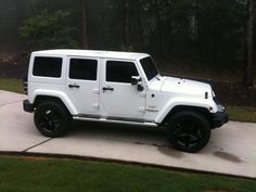 a white jeep is parked in front of some trees