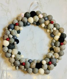 a wreath made out of felt balls on a marble counter top with a white ribbon