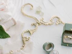 wedding rings and jewelry laid out on a white table cloth with flowers in the background