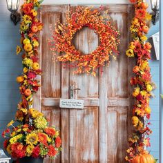 a wooden door decorated with fall flowers and pumpkins