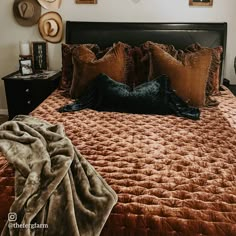 a bed with pillows and blankets on top of it in a room filled with pictures