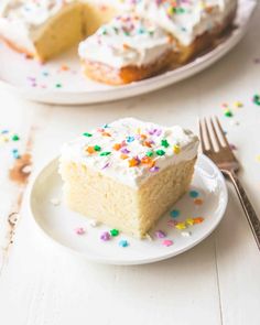 a slice of cake with white frosting and sprinkles on a plate