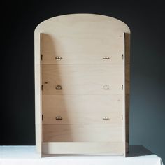 a wooden shelf sitting on top of a white cloth covered table next to a black wall