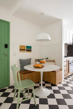 a kitchen with black and white checkered flooring, green doors and a round dining table