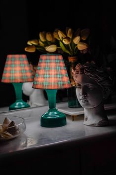 two lamps are sitting on a table next to a vase with tulips in it