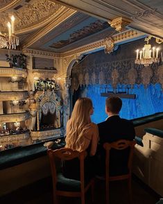 two people are sitting at a table in front of a stage with lights on it