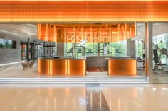 the inside of a gym with orange lighting and mirrors on the wall, as well as an exercise area