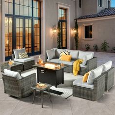 an outdoor living area with wicker furniture and fire pit in front of a house