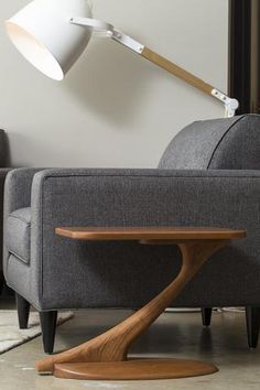 a grey couch with a wooden table in front of it and a white lamp on the side