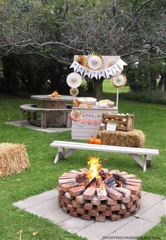 an outdoor bbq with fire pit, hay bales and decorations on the grass