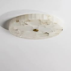 a close up of a light fixture on a white wall with a gold button in the middle