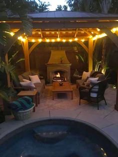 an outdoor living area with a fire place and patio furniture in the evening time,