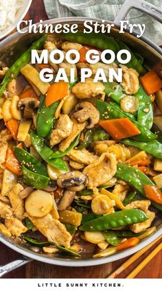 a pan filled with stir fry and vegetables on top of a wooden table next to chopsticks