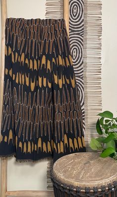 a brown and black blanket sitting on top of a wooden chair next to a plant