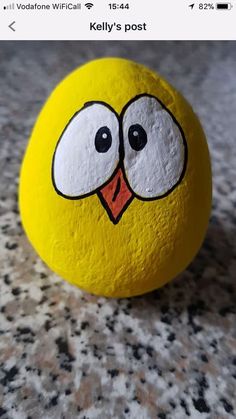 a yellow rock with a cartoon face painted on it's side, sitting on a granite surface