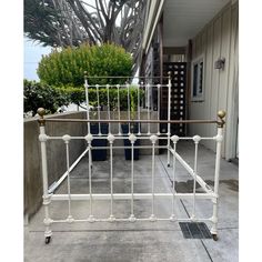 a white metal bed frame sitting on top of a cement floor next to a building