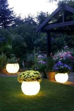 three large planters filled with flowers in the grass