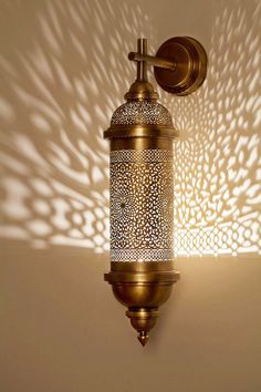 a wall mounted light fixture with a shadow cast on the wall behind it and a cross at the top