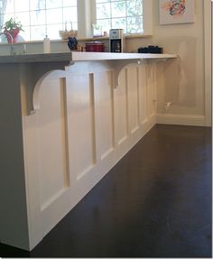 a kitchen with white cabinets and black flooring