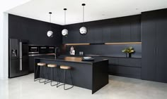 a modern kitchen with black cabinets and stools in front of an island countertop